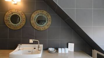 Un baño con una bañera blanca grande, dos espejos decorativos en la pared y un perchero para toallas.