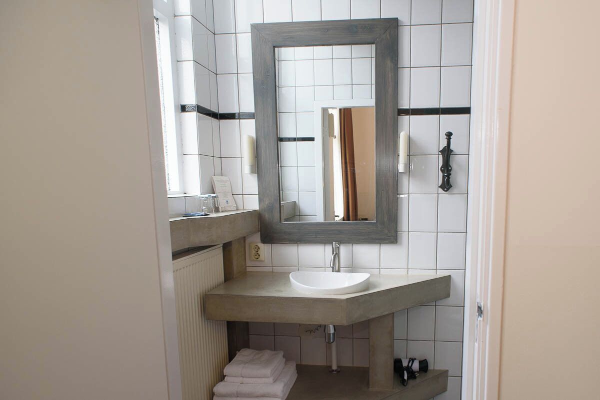 A bathroom with a large mirror, a white sink, and a towel rack.
