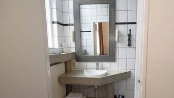 A bathroom with a large mirror, a white sink, and a towel rack.