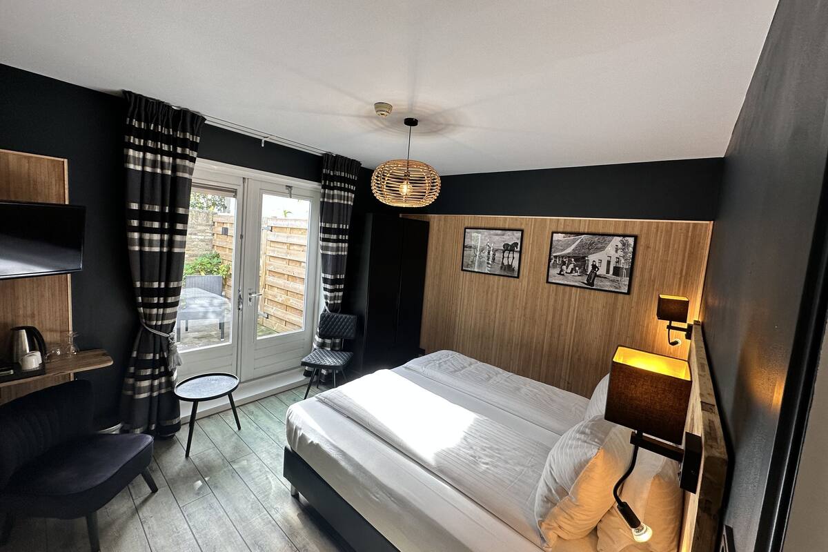Un dormitorio moderno con cama, escritorio, silla y una mesita.