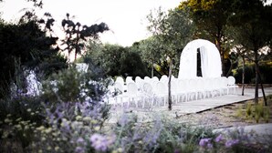 A white outdoor seating area with rows of chairs and a central archway, surrounded by greenery and flowers. - MUSE Saint Tropez (Ramatuelle)