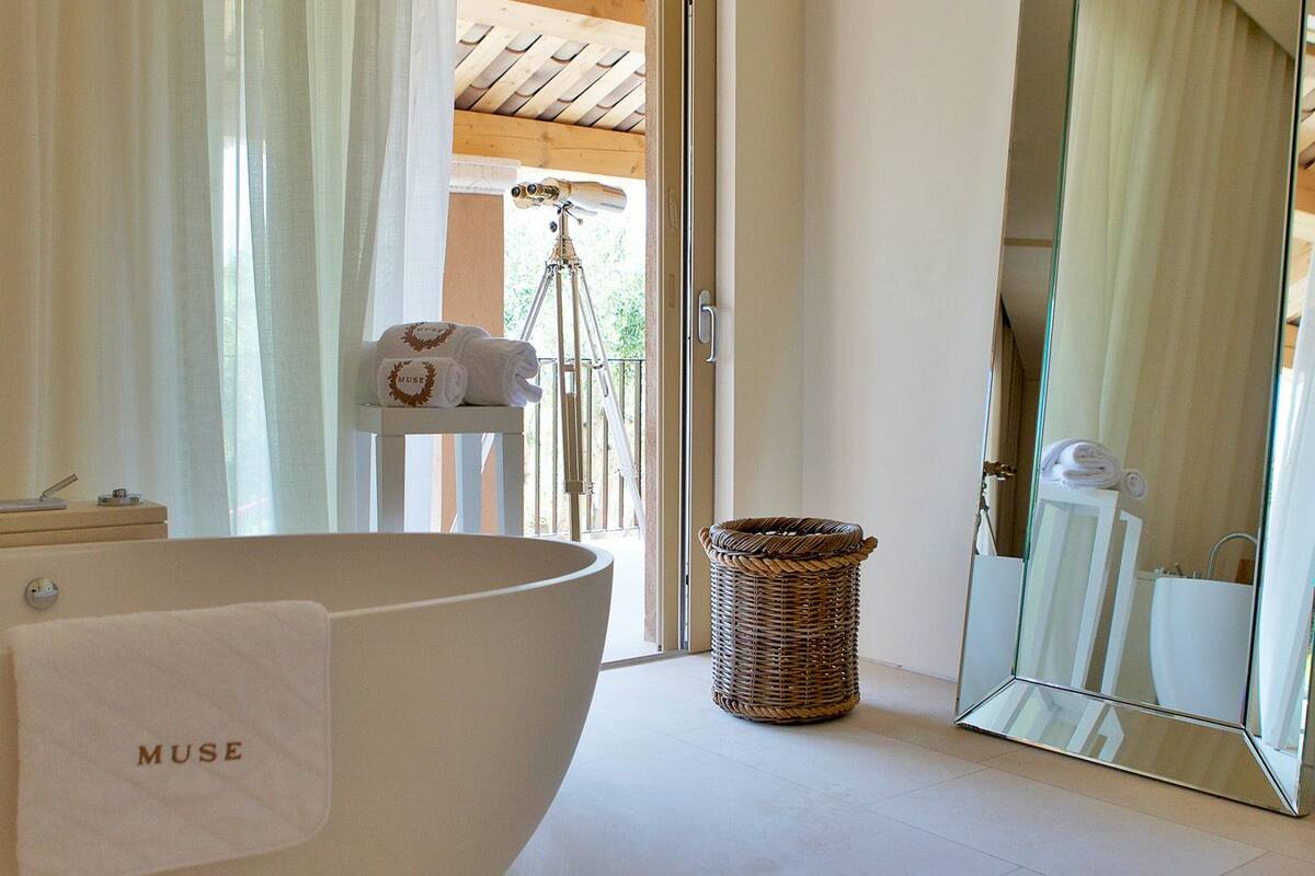A modern bathroom with a large bathtub, a wicker basket, and a mirror reflecting the room.