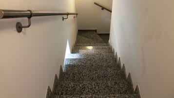 Un escalier avec des rampes en métal et un sol en granit.