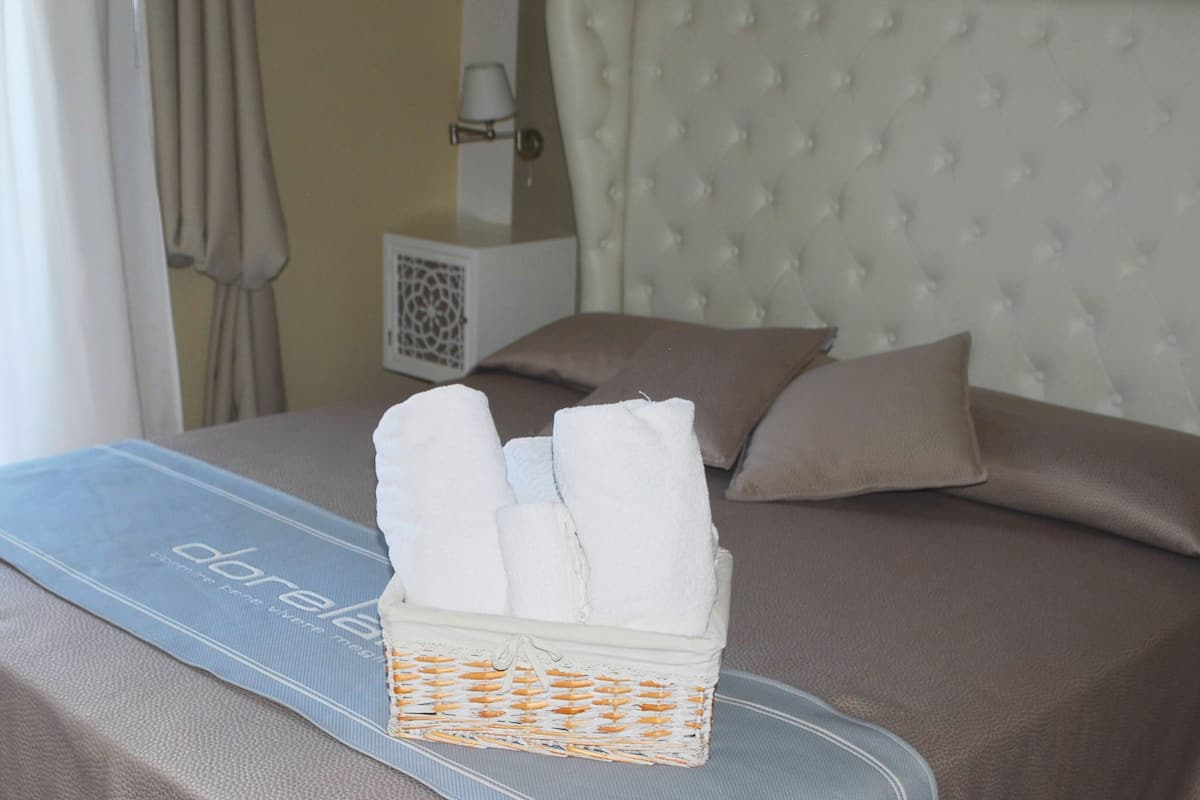 A neatly made bed with a blue bedspread, white towels, and a woven basket.