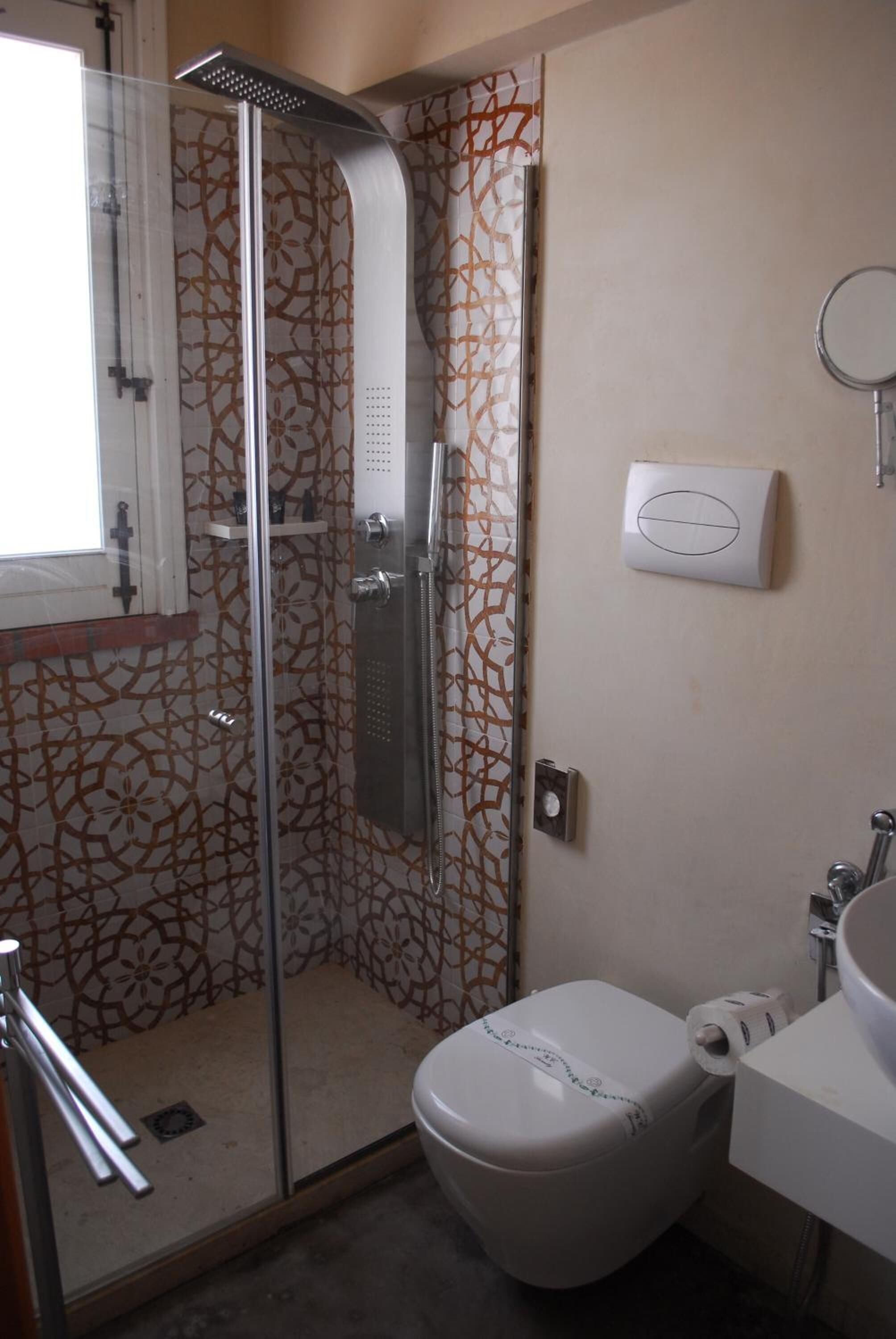 A bathroom with a glass-enclosed shower, a toilet, and a sink.