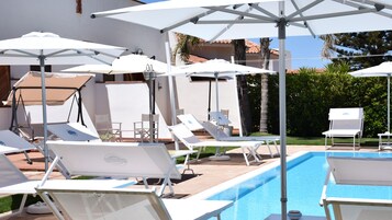 Una piscina al aire libre de temporada, sillones reclinables de piscina