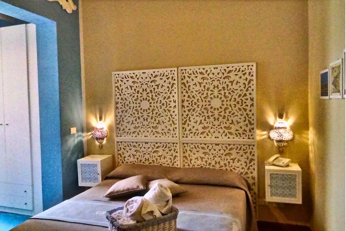A bedroom with a bed, pillows, a nightstand, and decorative wall panels.