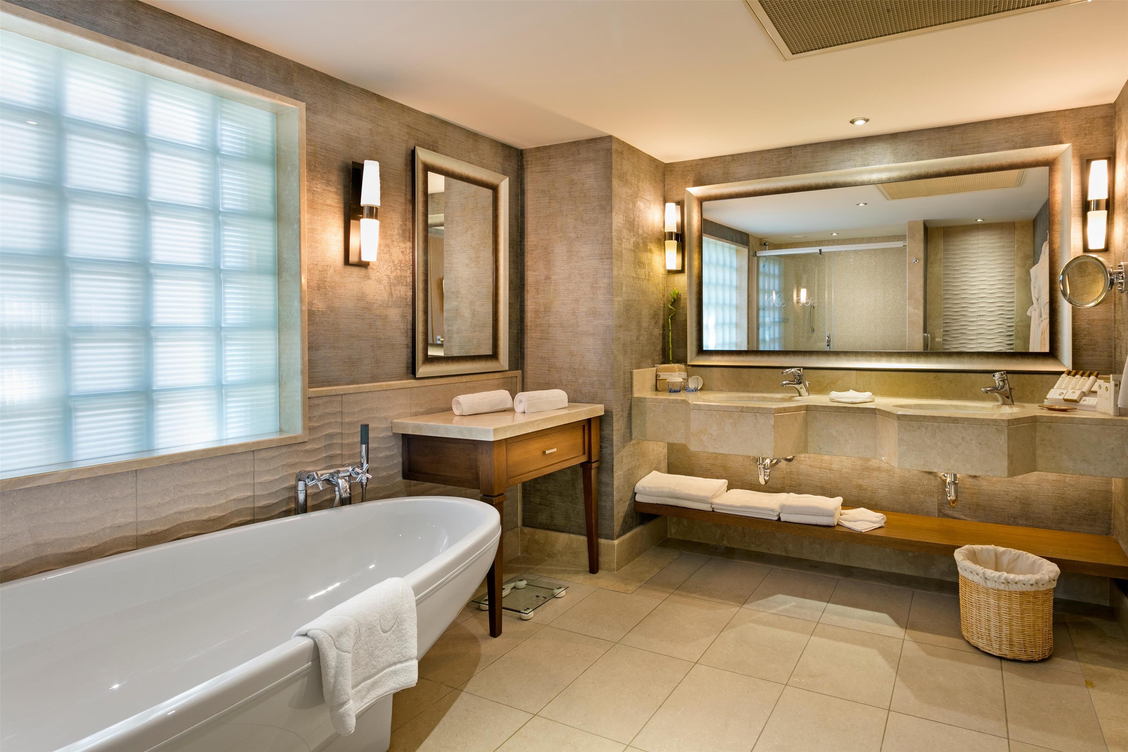 A modern bathroom with a freestanding bathtub, a vanity with a mirror, and a large mirror above the sink.