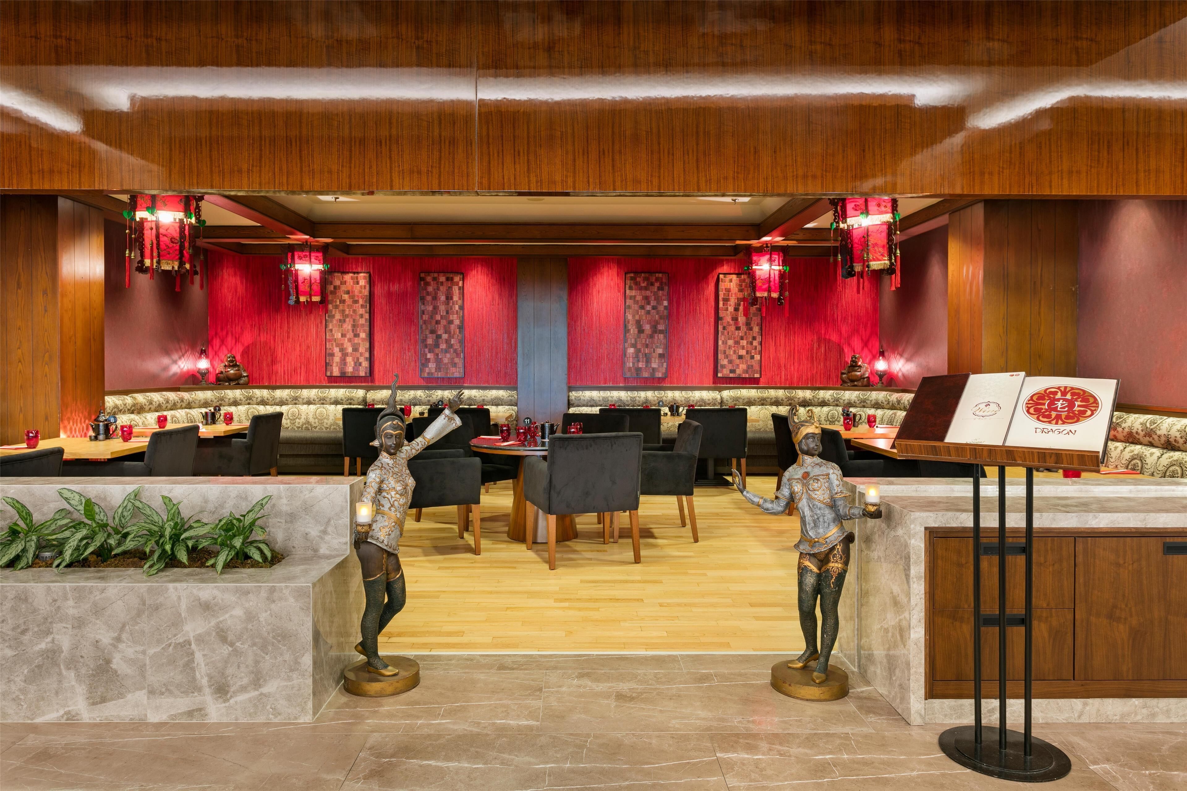 A restaurant with a wooden interior, red curtains, and a central dining area with tables and chairs.