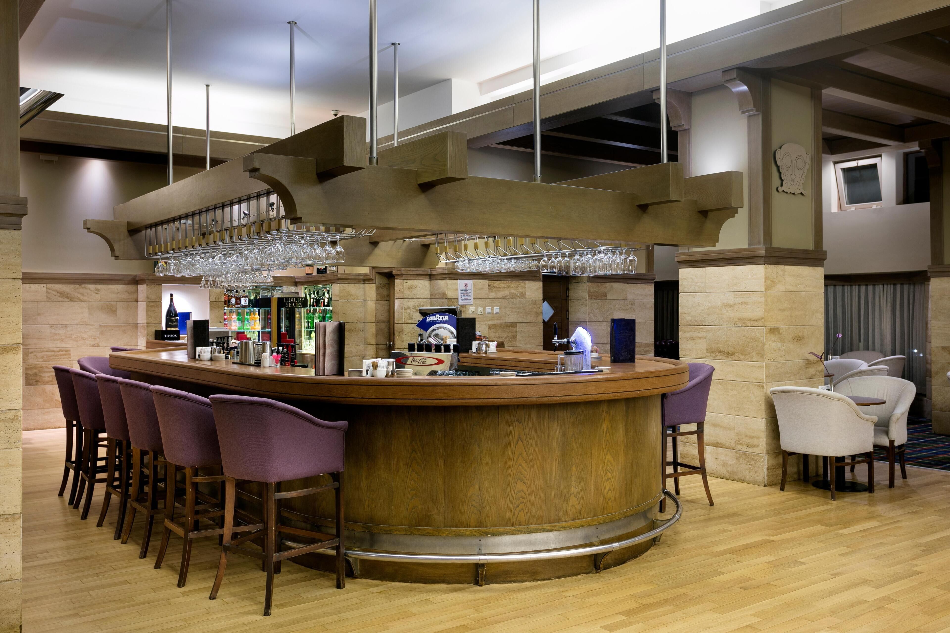 Zona de bar con mostrador de madera, taburetes y estante para vinos.