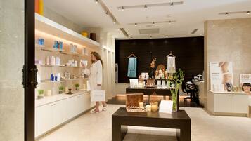 A modern spa interior with a reception desk, shelves with products, and a central table with candles.