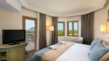A hotel room with a bed, a TV, a desk, a chair, and a view of the outdoors.
