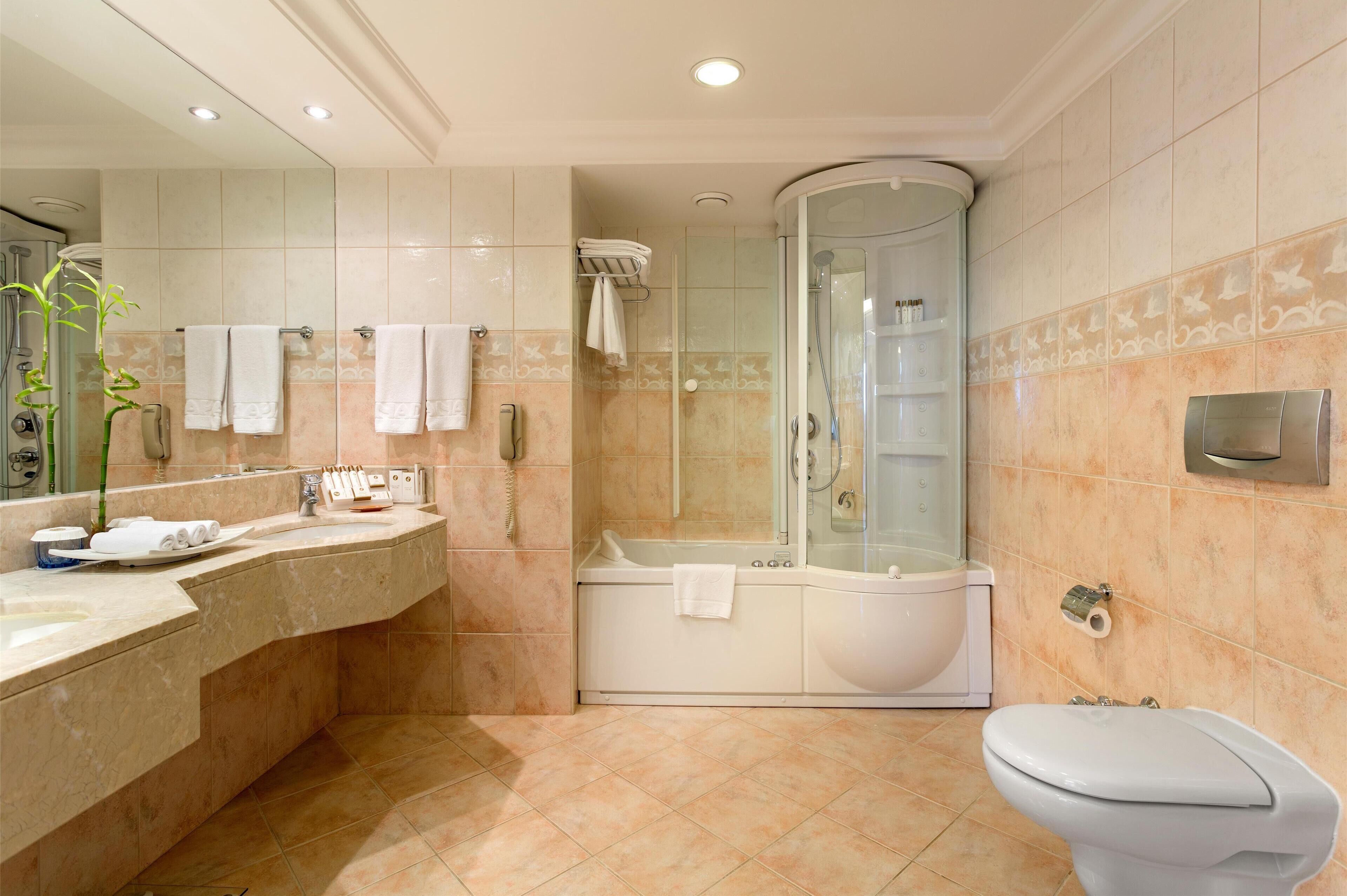 Een moderne badkamer met een douche met afgeronde wanden, een bad en een toilet.