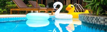A swimming pool with lounge chairs, a swan float, and a duck float.