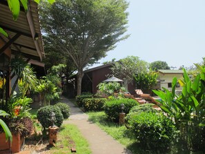 A pathway leading to a covered seating area with a tree and various plants. - Phuket Siam Villas (Chalong)