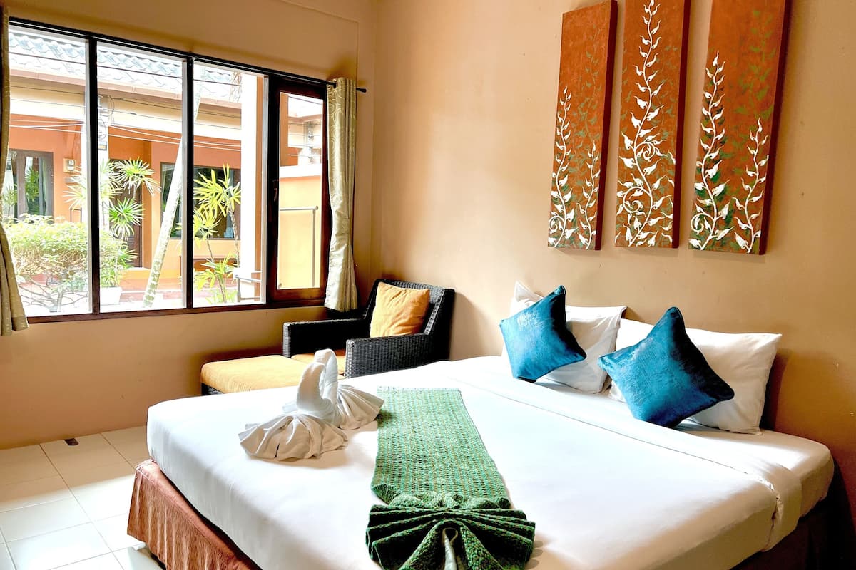 A hotel room with a bed, a chair, and a view of the outside.