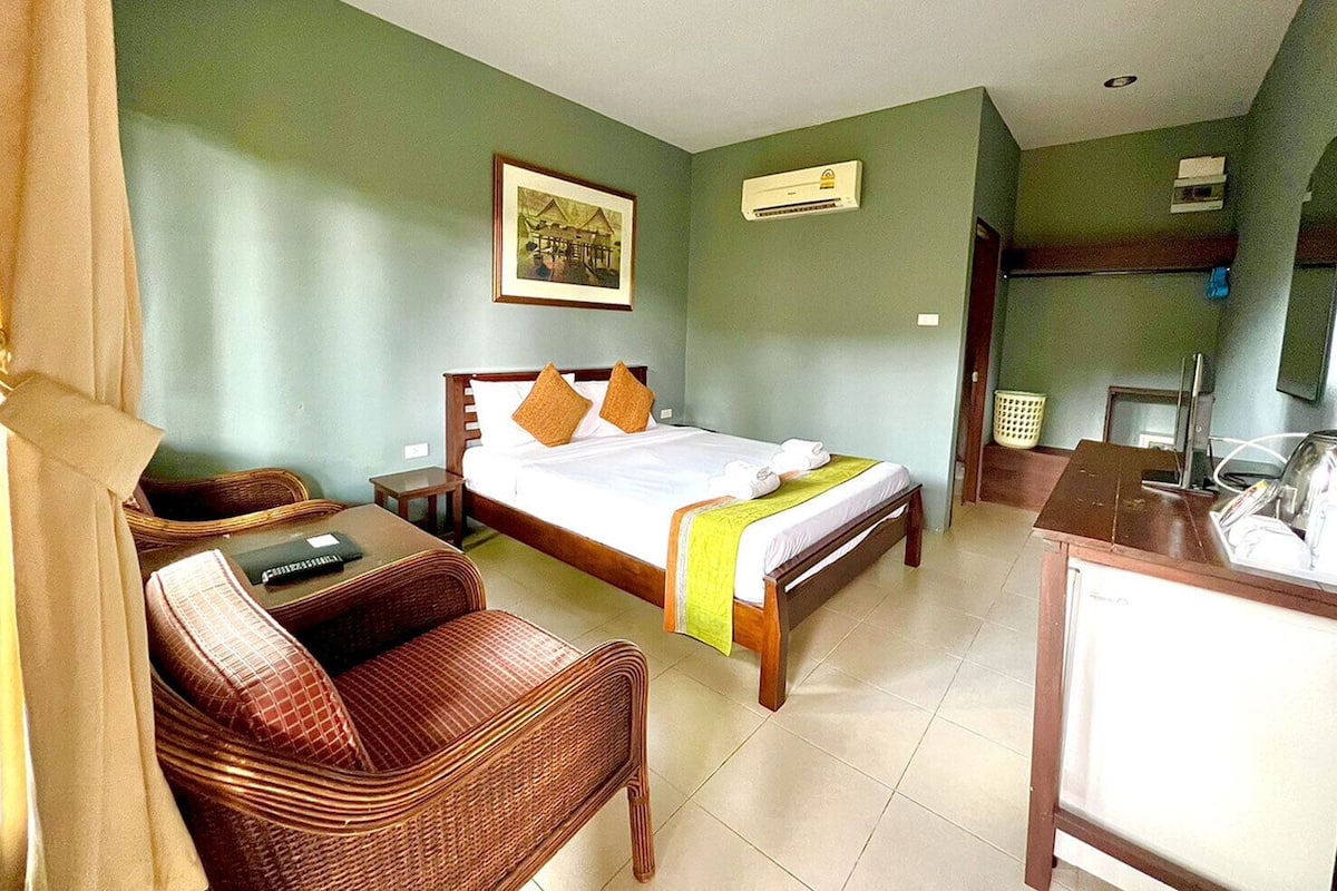 A hotel room with a bed, a desk, a chair, and a small table.
