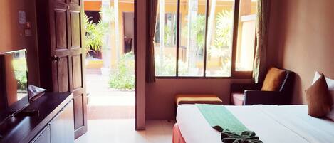 A hotel room with a bed, a desk, a TV, and a window with a view of the outside.