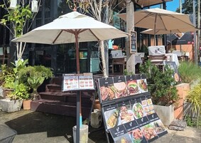 Un puesto de comida al aire libre con carteles de menú y sombrillas.