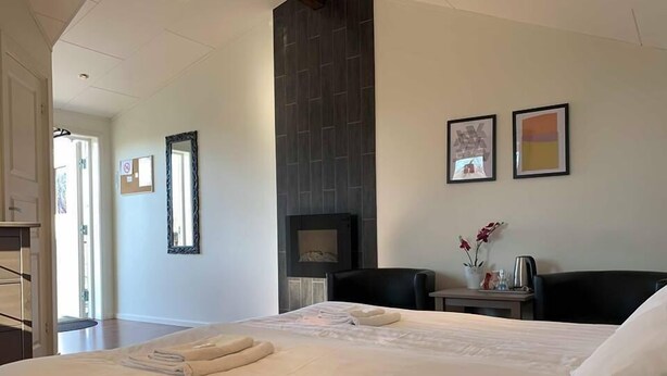 Ein Hotelzimmer mit einem großen Bett, einem Kamin, einem Schreibtisch mit Stuhl und zwei gerahmten Bildern an der Wand.