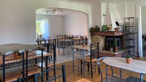 Ein Restaurant mit mehreren Tischen und Stühlen, einem Kamin aus Backsteinen und einer Deckenleuchte.