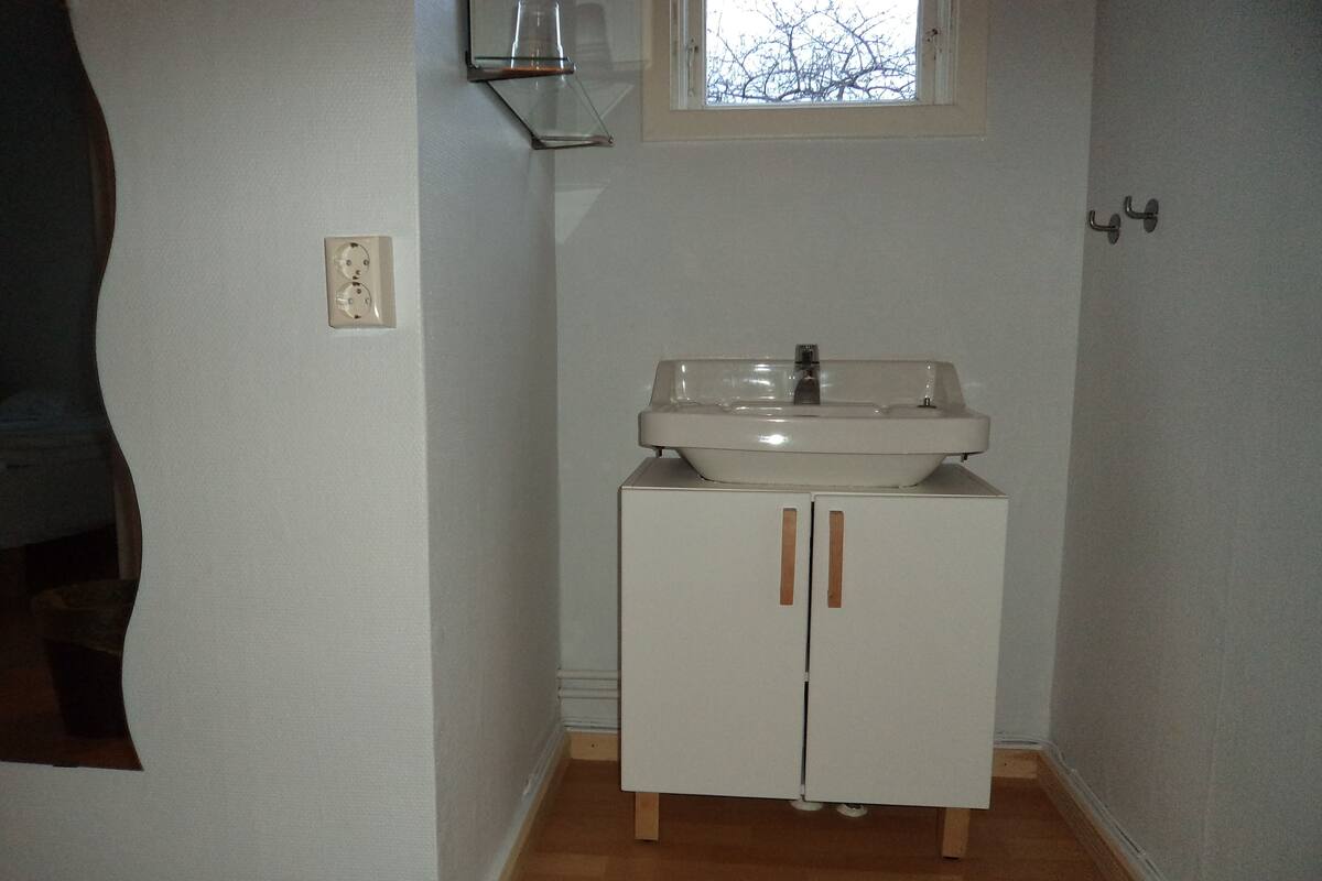 A bathroom with a white sink, wooden cabinets, and a window.