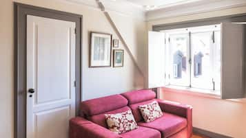 Ein Zimmer mit einem roten Sofa, einem gemusterten Teppich, einer weißen Tür und einer Deckenleuchte.