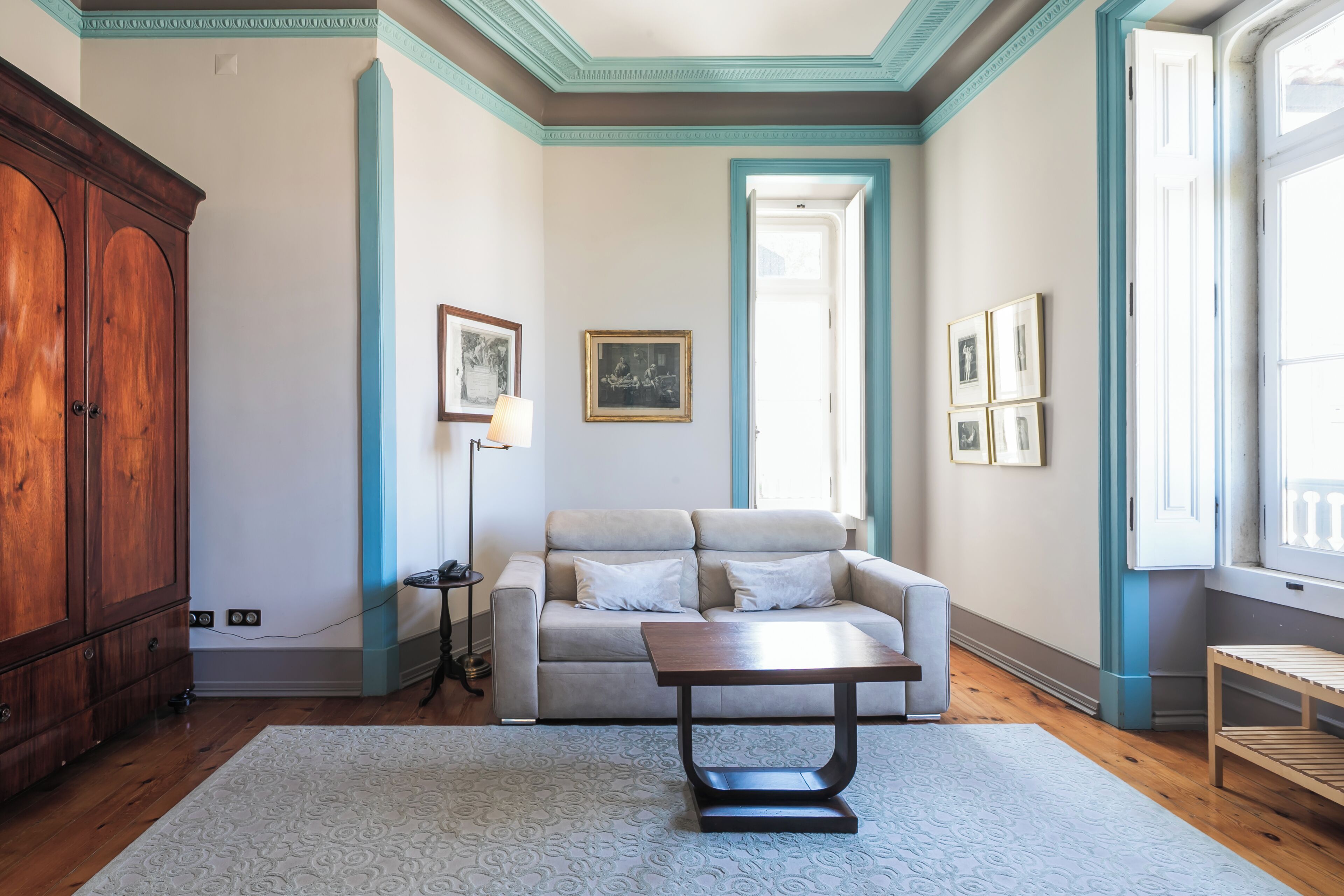 A room with a wooden cabinet, a sofa, a table, and a floor lamp.