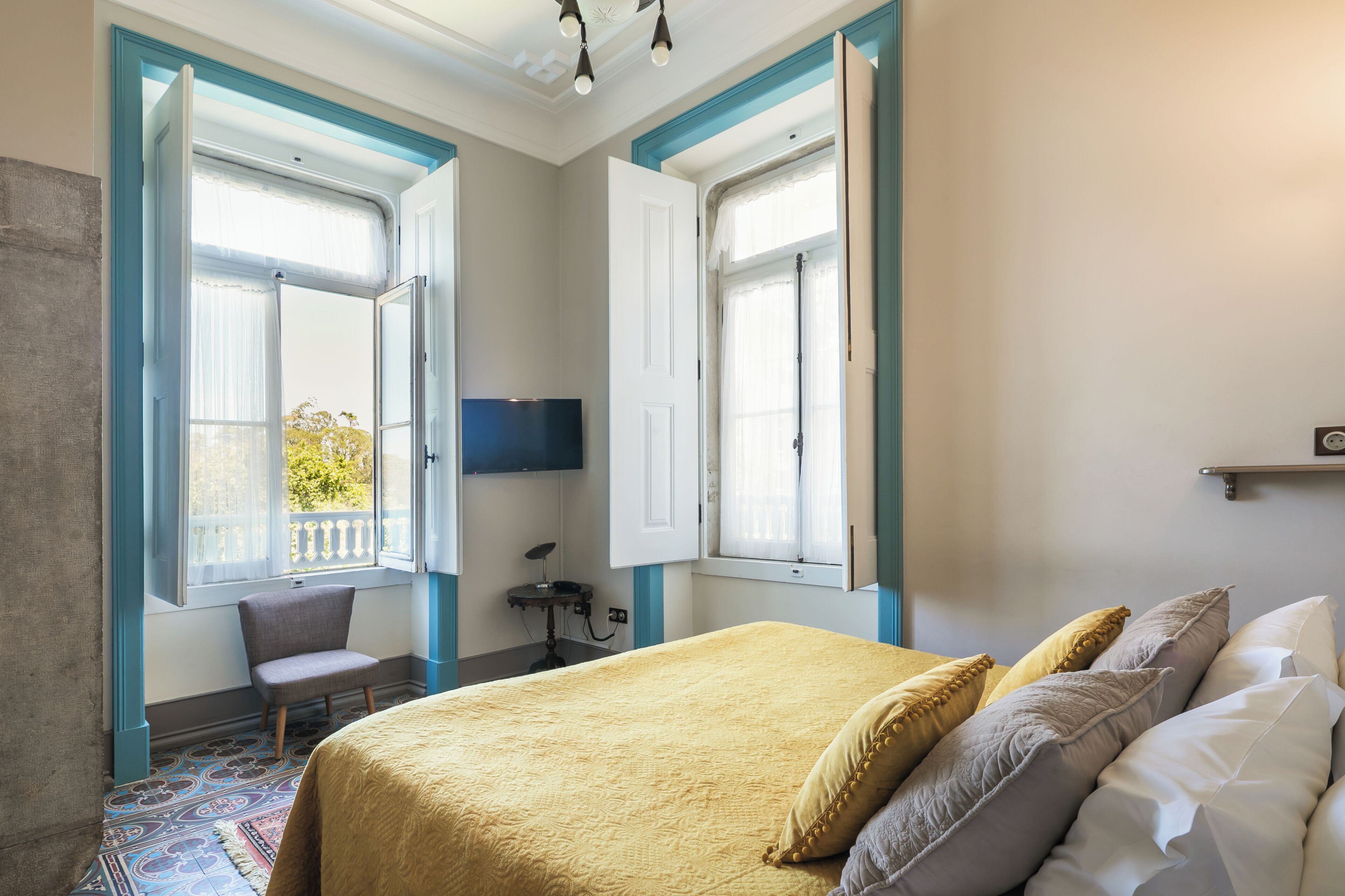 Un dormitorio con una cama, una silla, un escritorio y un televisor.