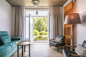A living room with a teal sofa, a black leather chair, a round table, and a floor lamp. - Chalet Saudade (Sintra)