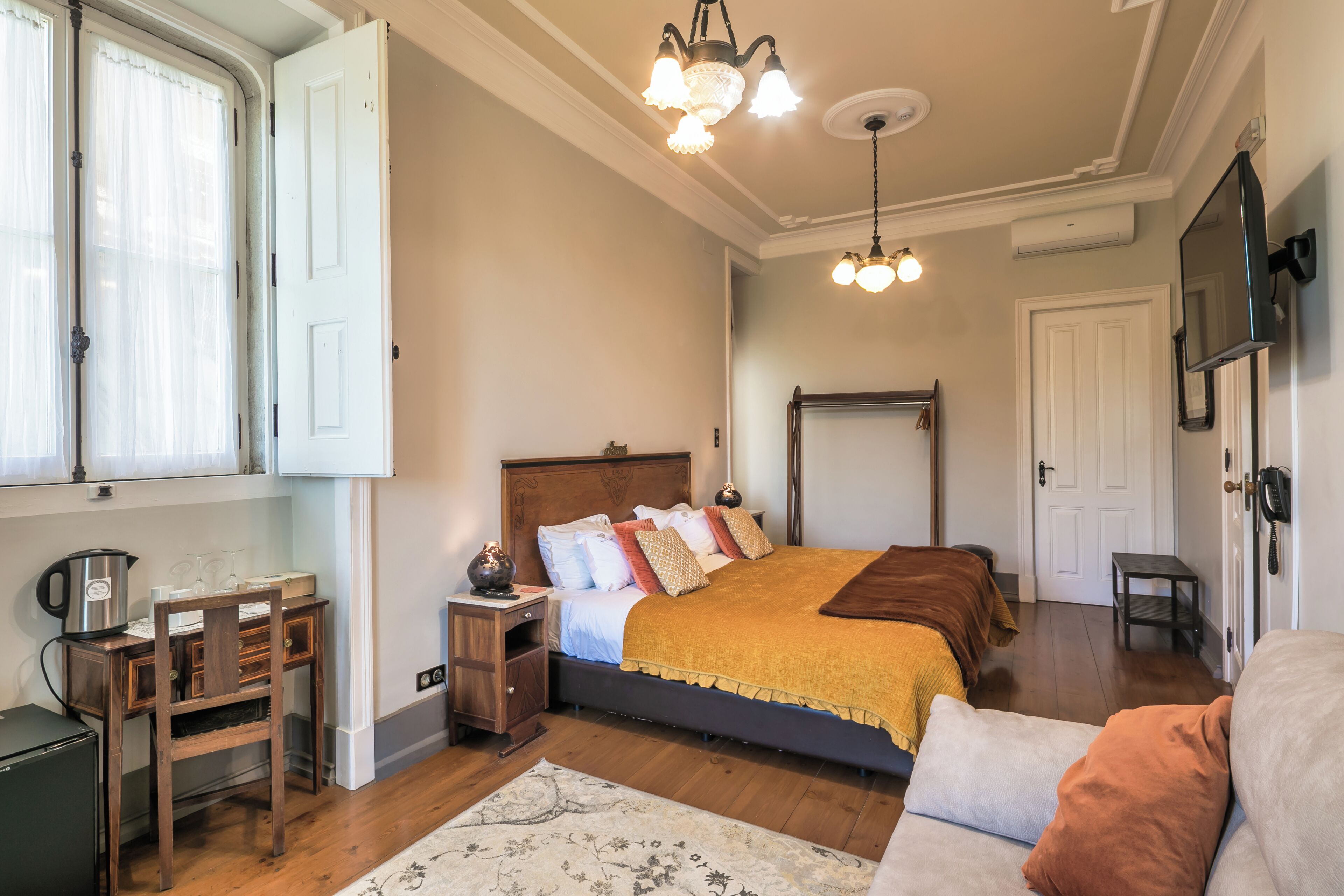 A bedroom with a bed, bedside tables, a desk, a chair, a rug, and a ceiling light fixture.