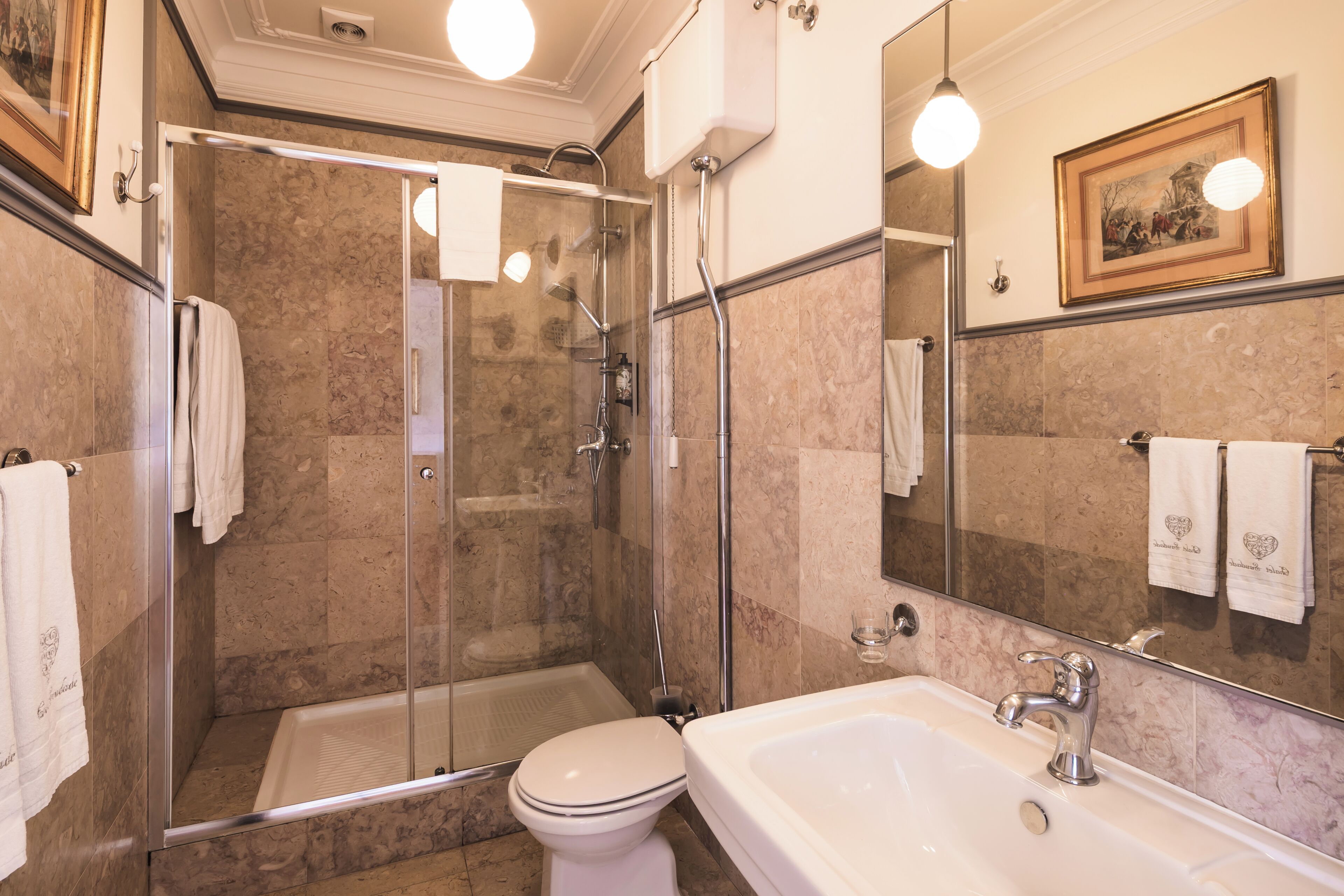 A bathroom with a glass-enclosed shower, a white toilet, and a sink with a mirror above it.