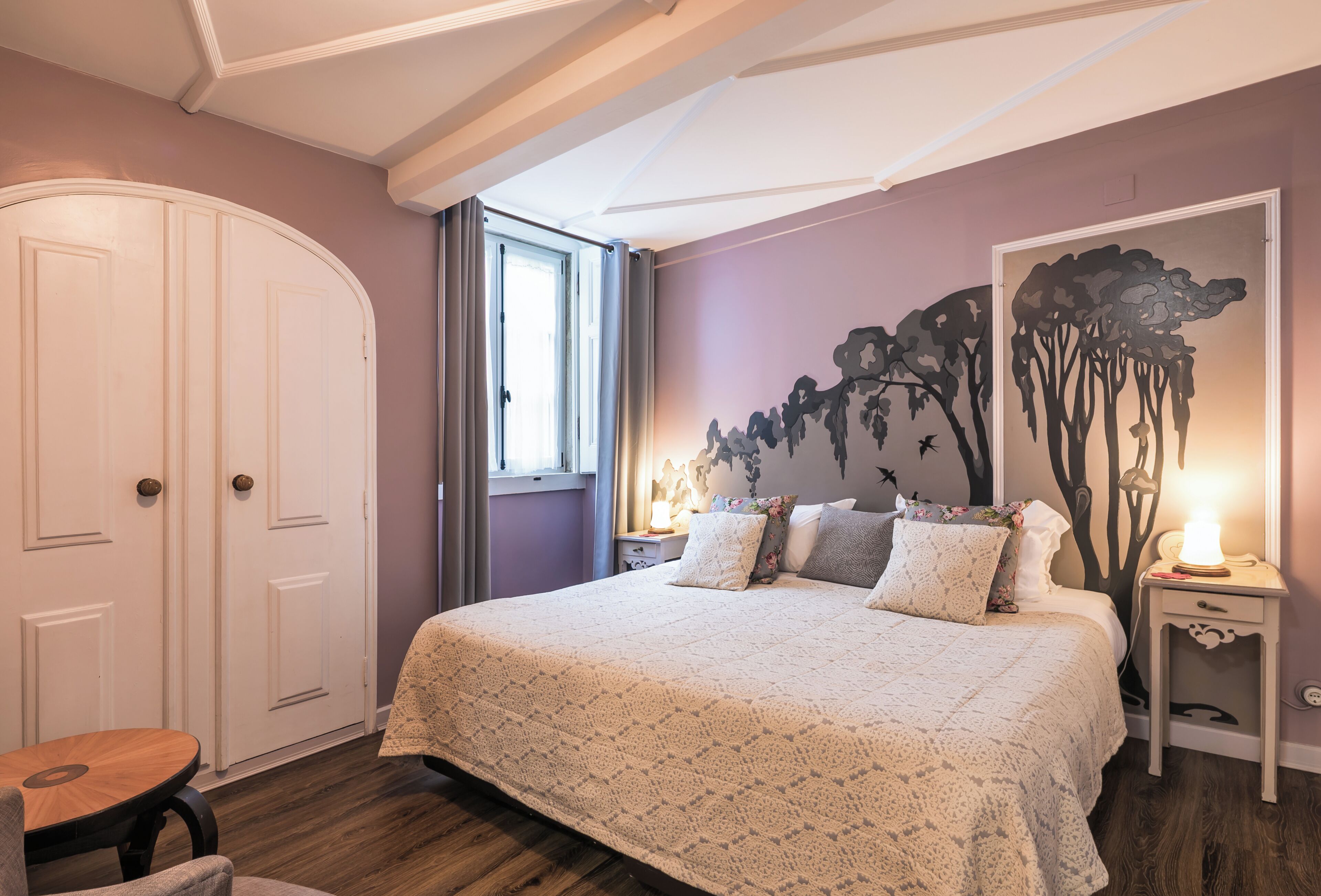 Ein Schlafzimmer mit einem großen Bett, einem Nachttisch, einem Sessel und einem Kleiderschrank.