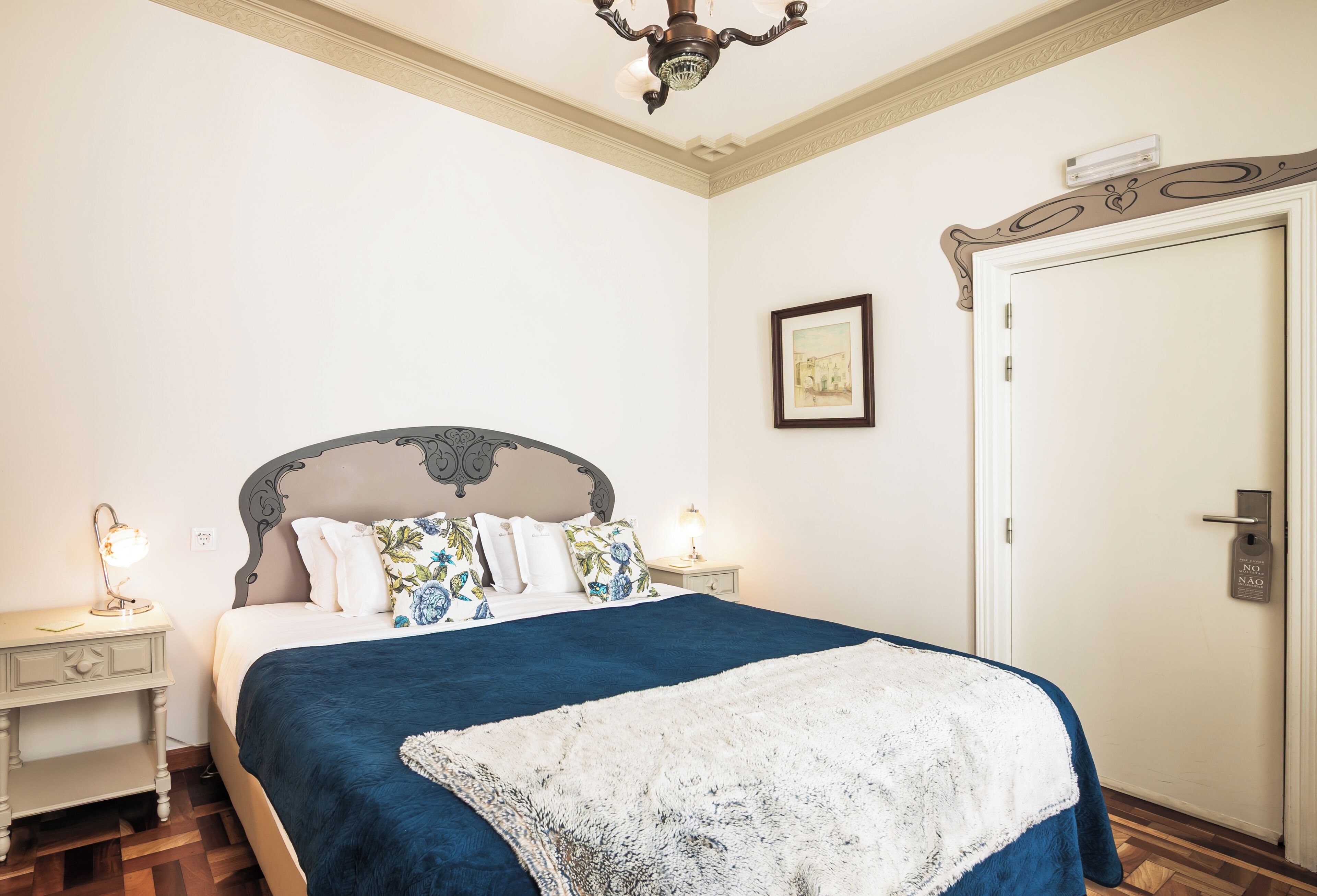 Un dormitorio con cama, mesitas de noche, una lámpara de techo y una puerta.