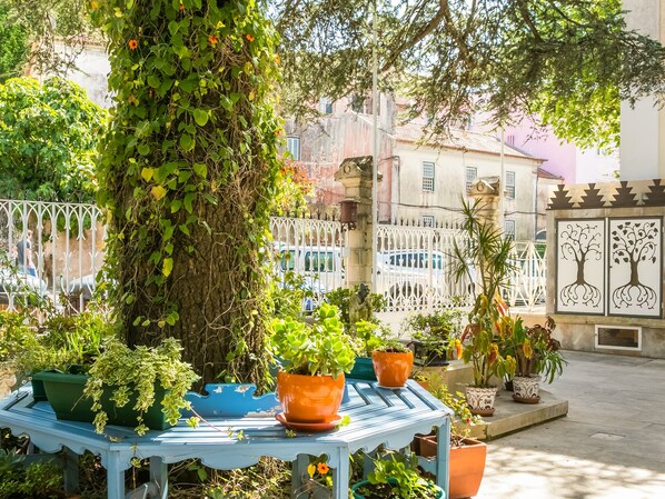 A courtyard with a variety of potted plants, a blue table, and a white fence. - Chalet Saudade (Sintra)