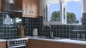 A kitchen with a stove, sink, and window with blinds. - Dialiskari Villas (Trifylia)