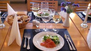 A dining table set with a plate of salmon and greens, wine glasses, and a candle. - Hotel Kong Valdemar (Vordingborg)