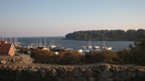 A coastal marina with boats docked, a stone wall in the foreground, and a small building with a red roof. - Hotel Kong Valdemar (Vordingborg)
