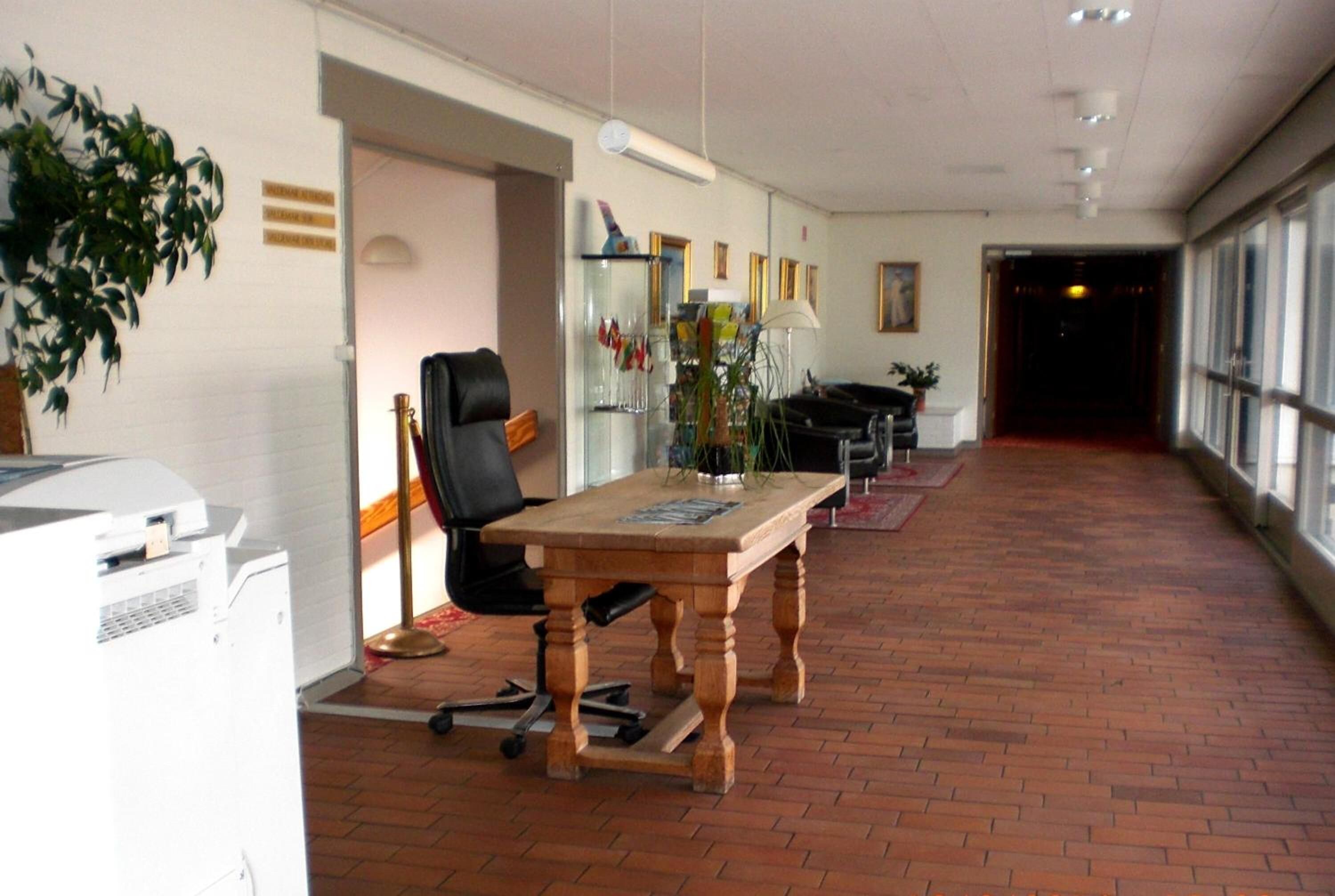 A spacious office with a long table, a black office chair, and a potted plant.