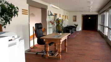 A spacious office with a long table, a black office chair, and a potted plant.