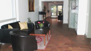 A spacious living area with a sofa, armchairs, and a coffee table. A painting is on the wall, and a plant is on a side table. - Hotel Kong Valdemar (Vordingborg)