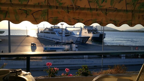 A ferry terminal with a view of the sea, a parked car, and a building with graffiti. - Oscar Hotel (Igoumenitsa)