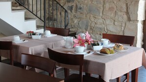 A dining area with stone walls, a staircase, and wooden chairs and tables. - Tenuta Zannafondo (Ragusa)