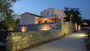 A stone house with a gravel driveway and a stone wall. - Tenuta Zannafondo (Ragusa)