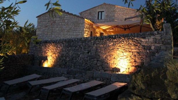 A stone building with outdoor seating and a stone wall. - Tenuta Zannafondo (Ragusa)