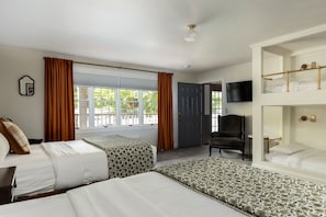 Une chambre d’hôtel avec deux lits, un bureau, une chaise, une télévision et une fenêtre avec des rideaux.