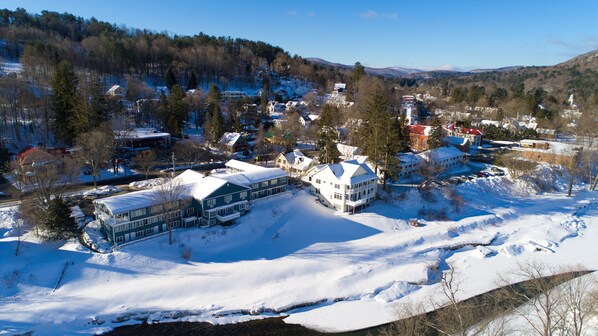 Una zona residencial cubierta de nieve con casas y un edificio grande con muchas ventanas y una entrada destacada.