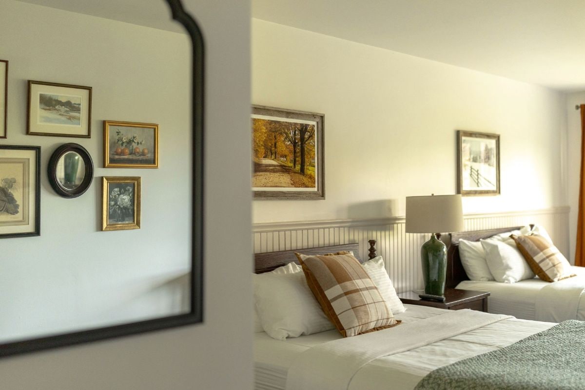 Una habitación de hotel con una cama, una mesita de noche, una lámpara y cuadros en la pared.