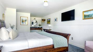 A hotel room with a wooden bed, a flat-screen TV, a desk with a lamp, and a chair.