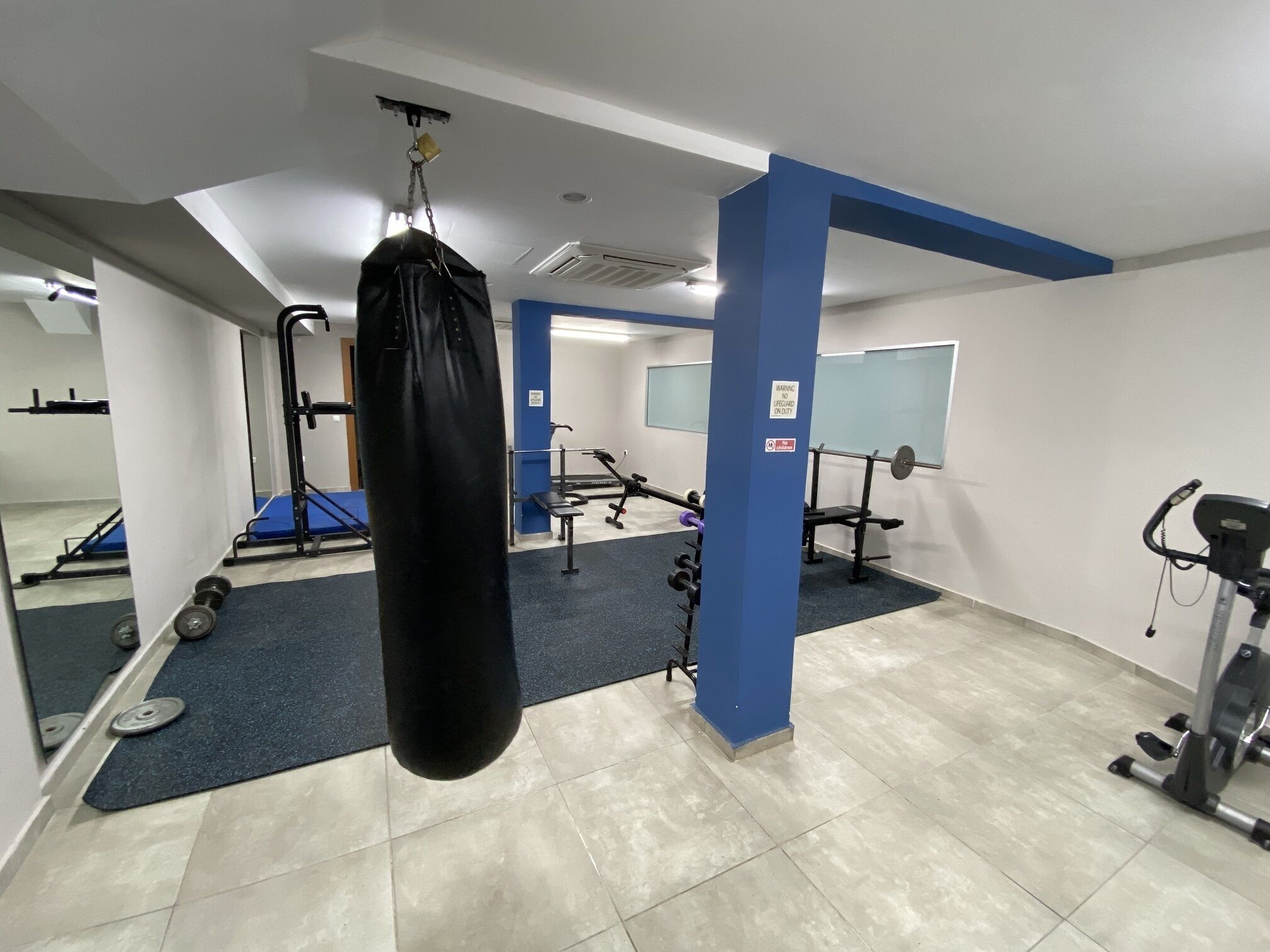 A gym with a punching bag, weightlifting equipment, and exercise machines.